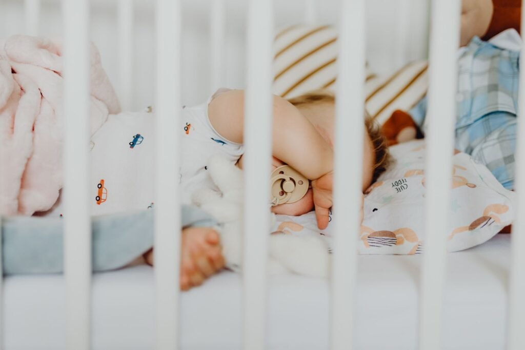 A baby sleeping safely on their back in a bare crib
