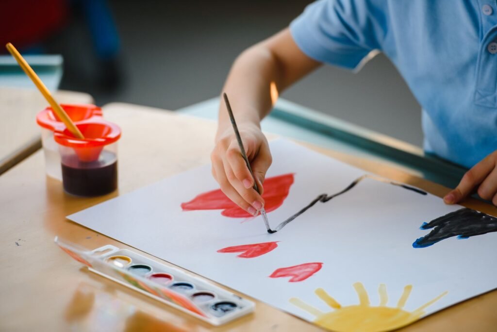 A child happily painting at the kitchen table