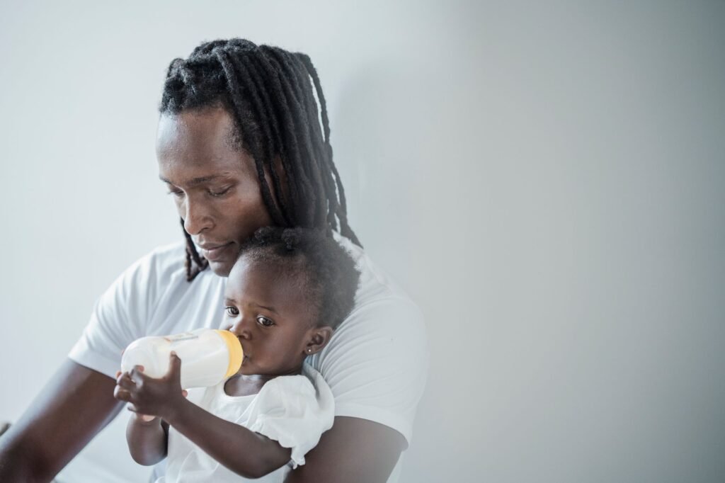 A father bottle feeding his baby while holding them close