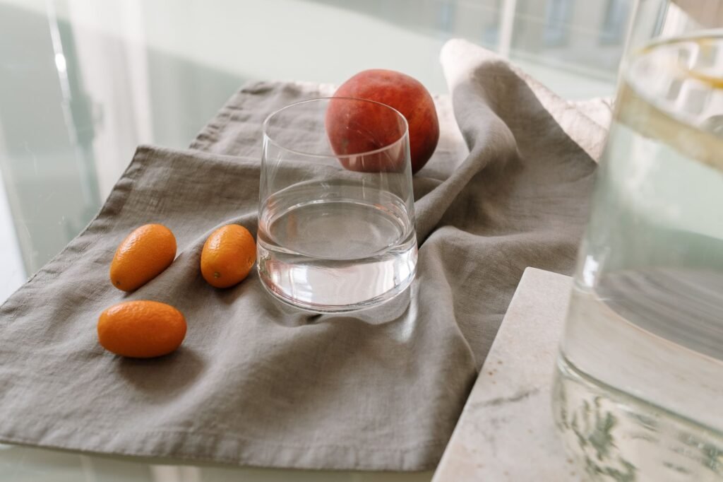 A glass of water with fresh fruit on a kitchen counter