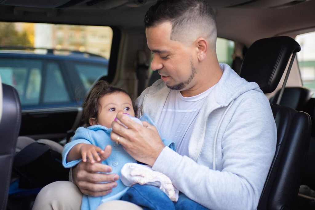 A parent carefully tightening a child's car seat harness