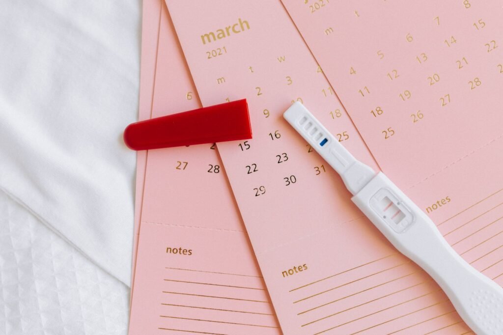 A pregnancy test and calendar laid out on a table