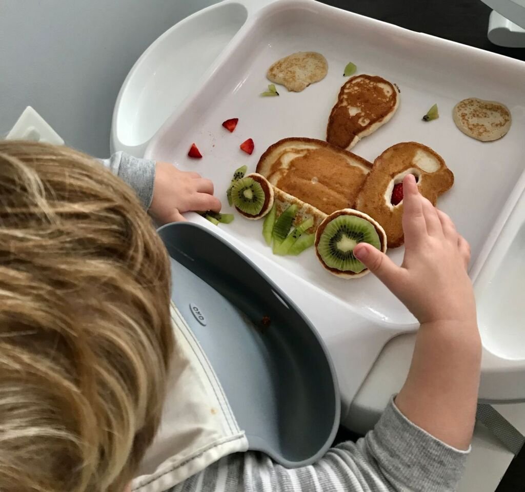 A toddler happily enjoying their breakfast, showcasing healthy food choices