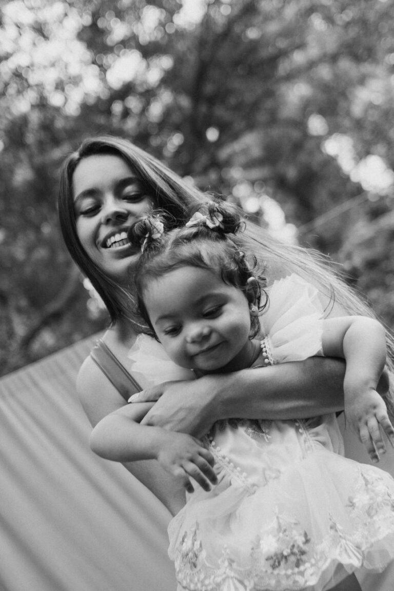 A joyful mother holding her baby daughter outdoors. Black and white image.