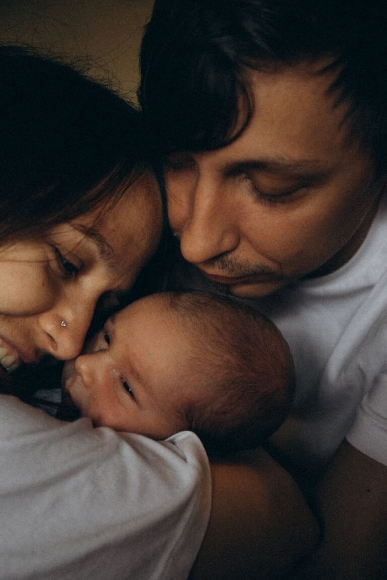 Heartwarming close-up of parents lovingly embracing their newborn child indoors.