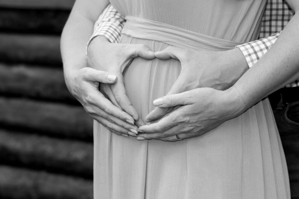 Hands gently resting on an early pregnancy bump