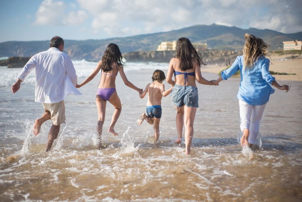 A family having fun running into the ocean on a sunny beach day in Portugal