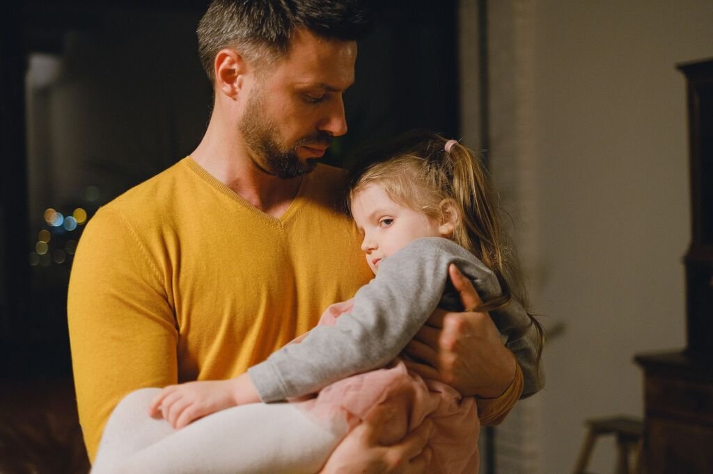 A father gently cradling his young daughter