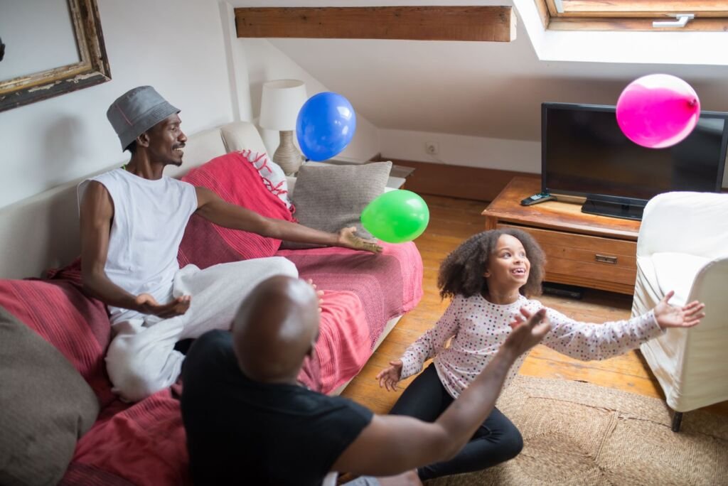 A joyful family plays with balloons at home