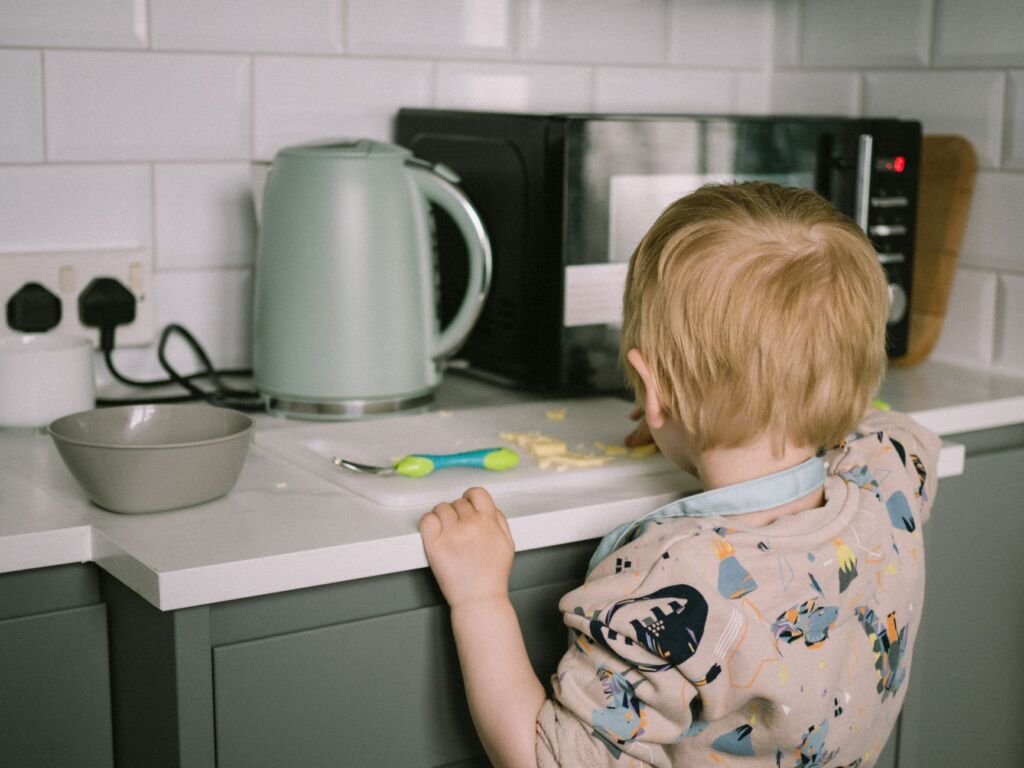 A toddler helping in the kitchen with snack preparation