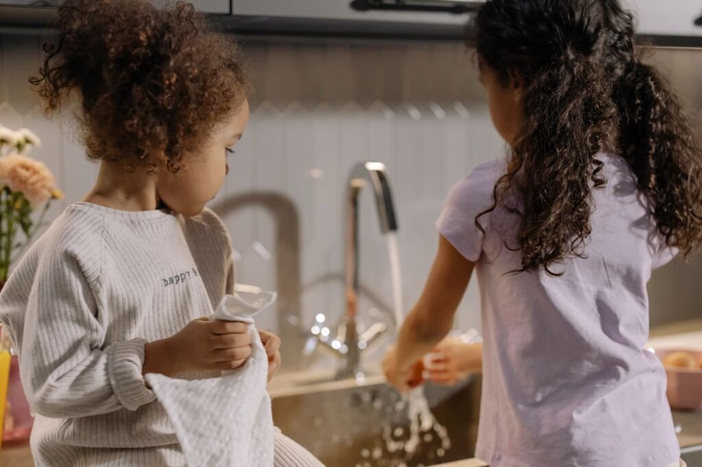 Two young girls washing dishes together in a cozy kitchen setting